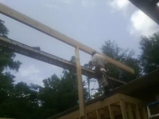 Carpenter setting a ridge beam over a new addition frame — Ice Dam Removal by Roofing Brothers in Wray