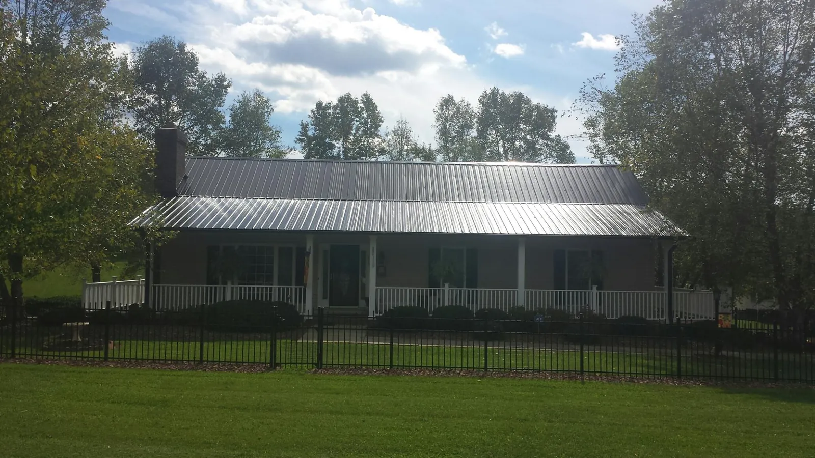 Gray metal roof on a brick ranch with a full width front porch — Gutter Guard Installation work by our crew in Wray