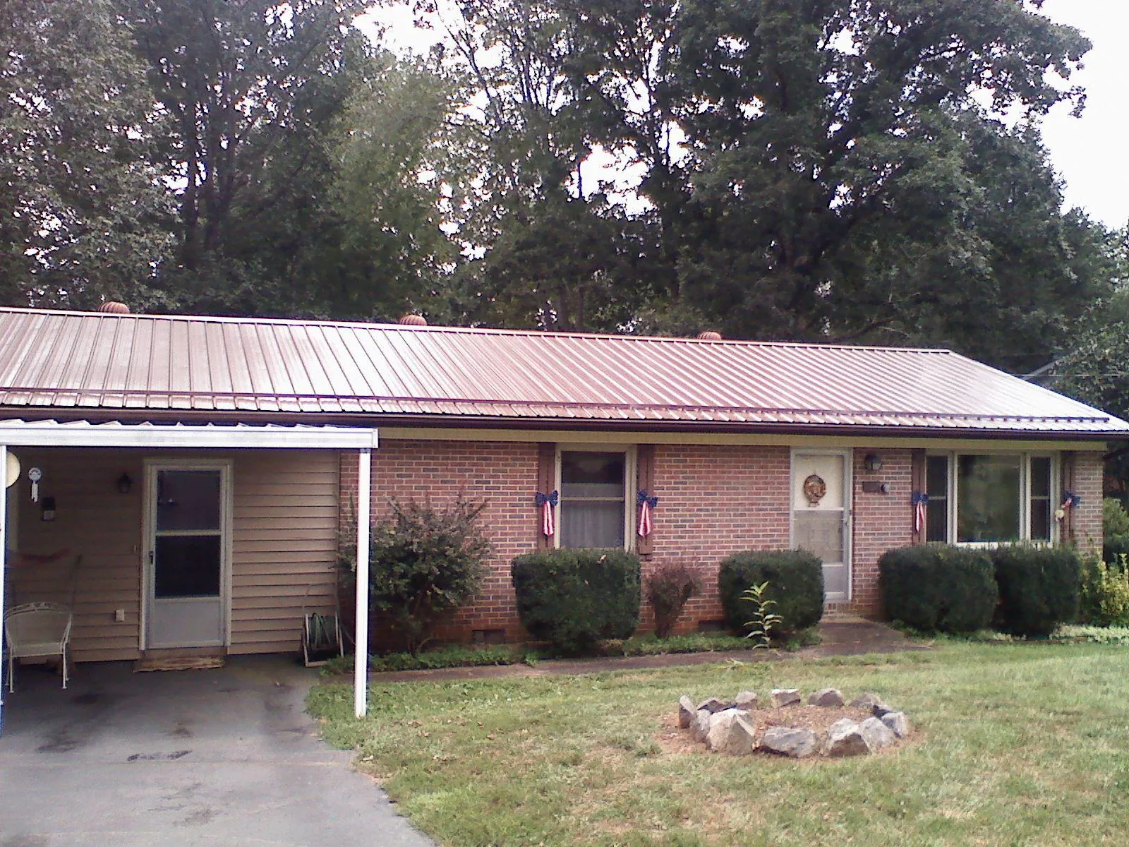 Bronze metal roof and carport on a brick ranch home — Roof Repair work by our crew in Wray