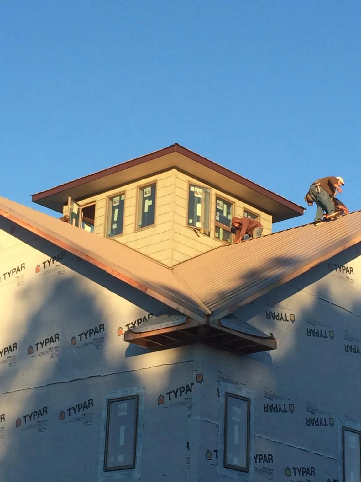 Roofers working around a rooftop cupola on a new metal roof at sunset — Roof Waterproofing in Wray by Roofing Brothers